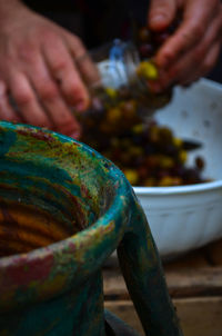 Cropped hands filling olive pickle in jar