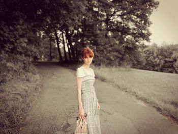 Portrait of young woman standing on road