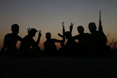 Silhouette people against clear sky during sunset