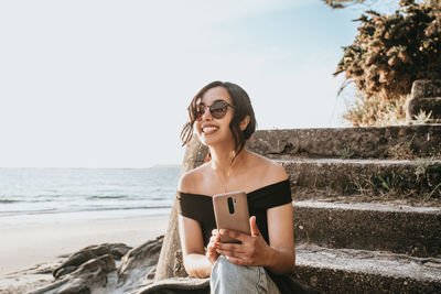 Portrait of young woman standing against sea