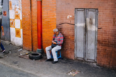 Full length of boy sitting on brick wall