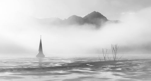 Panoramic foggy landscape with a sunken church in a muddy pond.