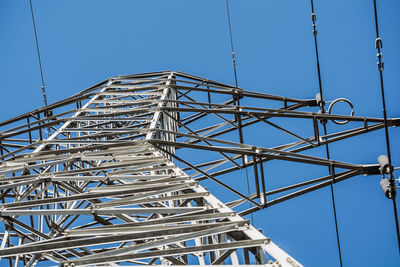 Low angle view of electricity pylon against clear blue sky