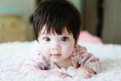 Close-up of cute baby girl lying down on bed