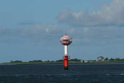 Lighthouse by sea against sky