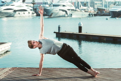 Full length of man doing yoga on pier