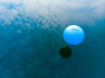 Blue hot air balloon flying over sea