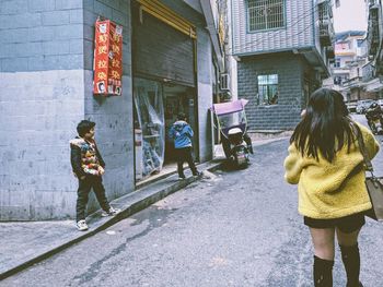 Rear view of people walking on street in city