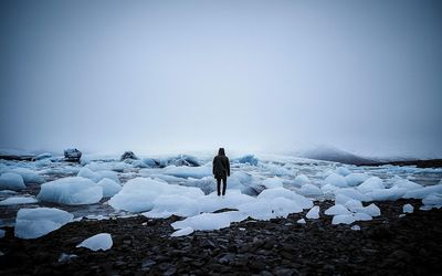 Rear view of woman on frozen landscape against clear sky