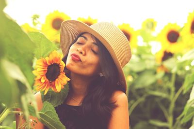 Portrait of young woman with hat against plants