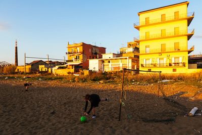 People playing on beach against buildings in city