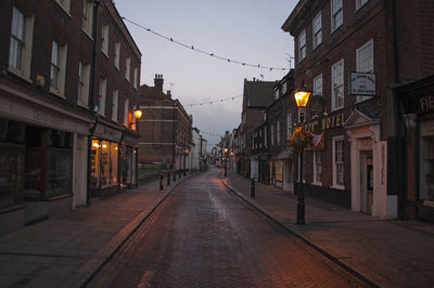 Empty road along buildings at dusk