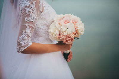 Midsection of bride holding bouquet