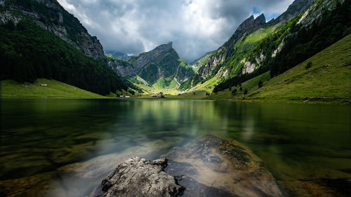 Scenic view of lake by mountains against sky