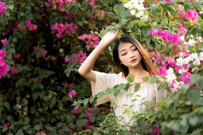 Portrait of beautiful woman standing by pink flower