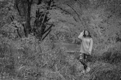 Portrait of beautiful girl standing amidst plants against tree