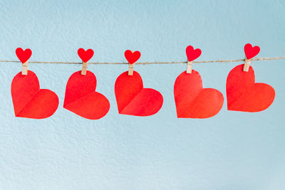 Low angle view of red heart shape hanging against white background