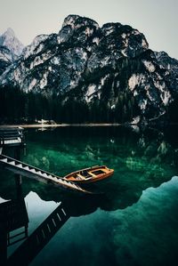 Boat moored in lake against rocky mountains