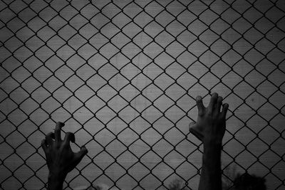 Shadow of person hand on fence against sky