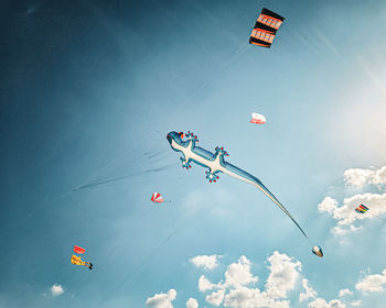 Low angle view of people paragliding against sky