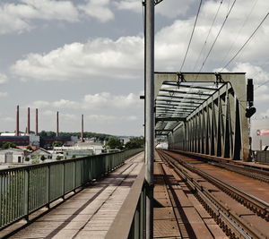 Railway bridge against cloudy sky in city