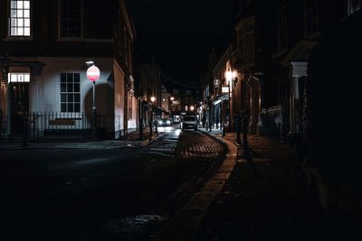 Illuminated street amidst buildings in city at night