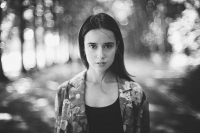 Portrait of young woman standing against trees