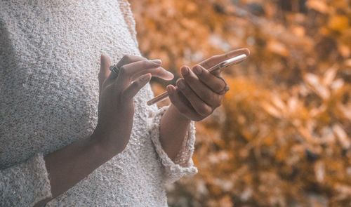 Close-up of hand holding smart phone during autumn