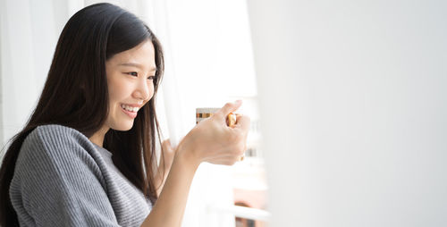 Portrait of smiling young woman holding mobile phone