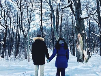 Rear view of couple standing in forest during winter