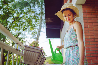 Young woman wearing hat standing against plants