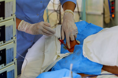 Midsection of woman giving injection to patient in hospital