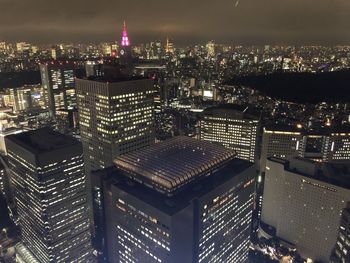 Illuminated modern buildings in city against sky at night