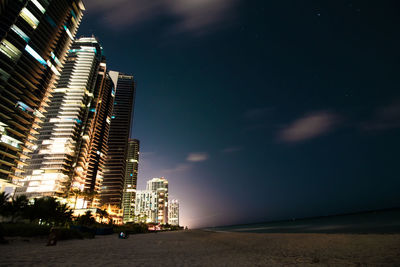 Buildings by beach in city at night