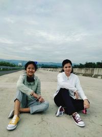 Portrait of man sitting on sand at beach against sky