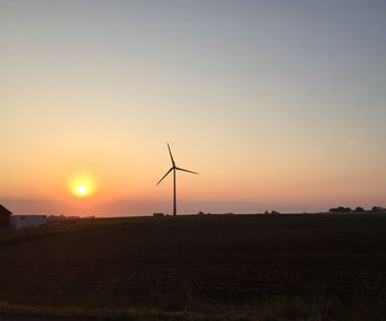 Silhouette of wind turbines in field