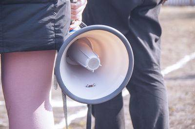 Midsection of woman holding umbrella standing outdoors