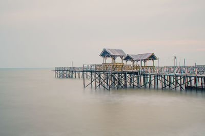 Lifeguard hut on pier by sea against sky