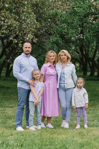 Family portrait of parents, children and grandmother in spring in a park or a blooming garden