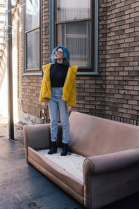 Full length of woman on sofa against building