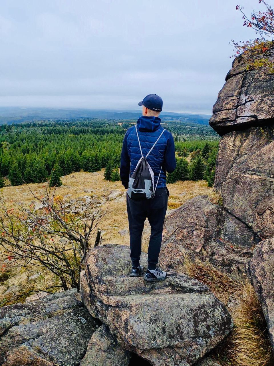 REAR VIEW OF MAN STANDING ON ROCK