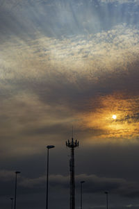 Low angle view of silhouette telephone pole against sky during sunset
