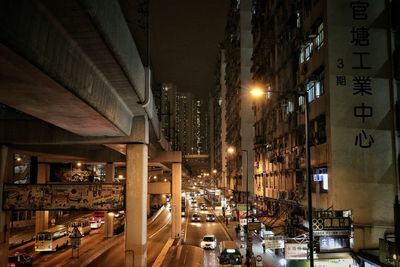 Bridge by buildings in city at night