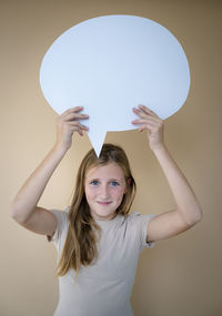 Portrait of smiling young woman with balloons against wall