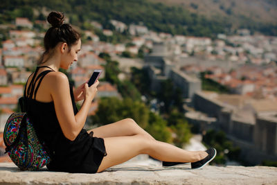 Woman using mobile phone on wall