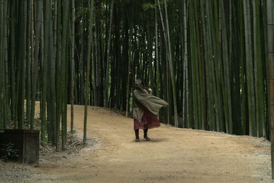 Rear view of woman walking on footpath in bamboo forest