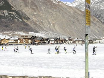 People skiing on snow covered field against mountains