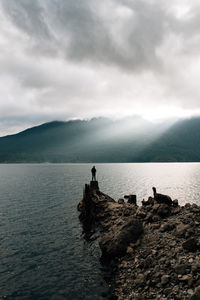 People on sea by mountains against sky