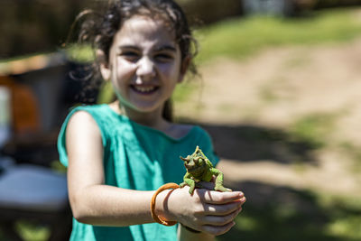 Portrait of smiling girl holding iguana