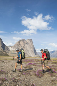 Two backpackers hiking through alpine meadow, akshayak pass